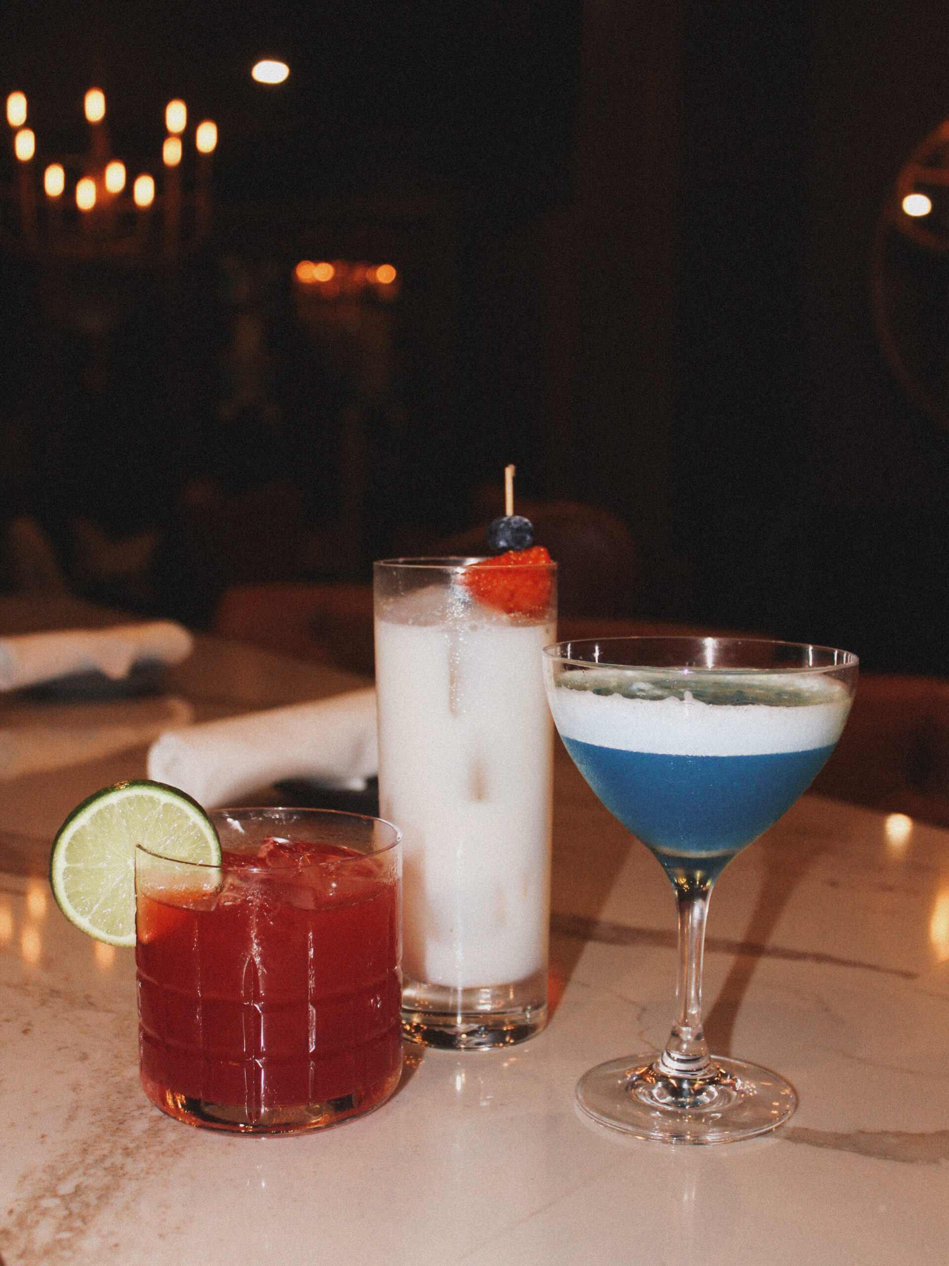 Red, white, and blue cocktails in a dark elegant bar.