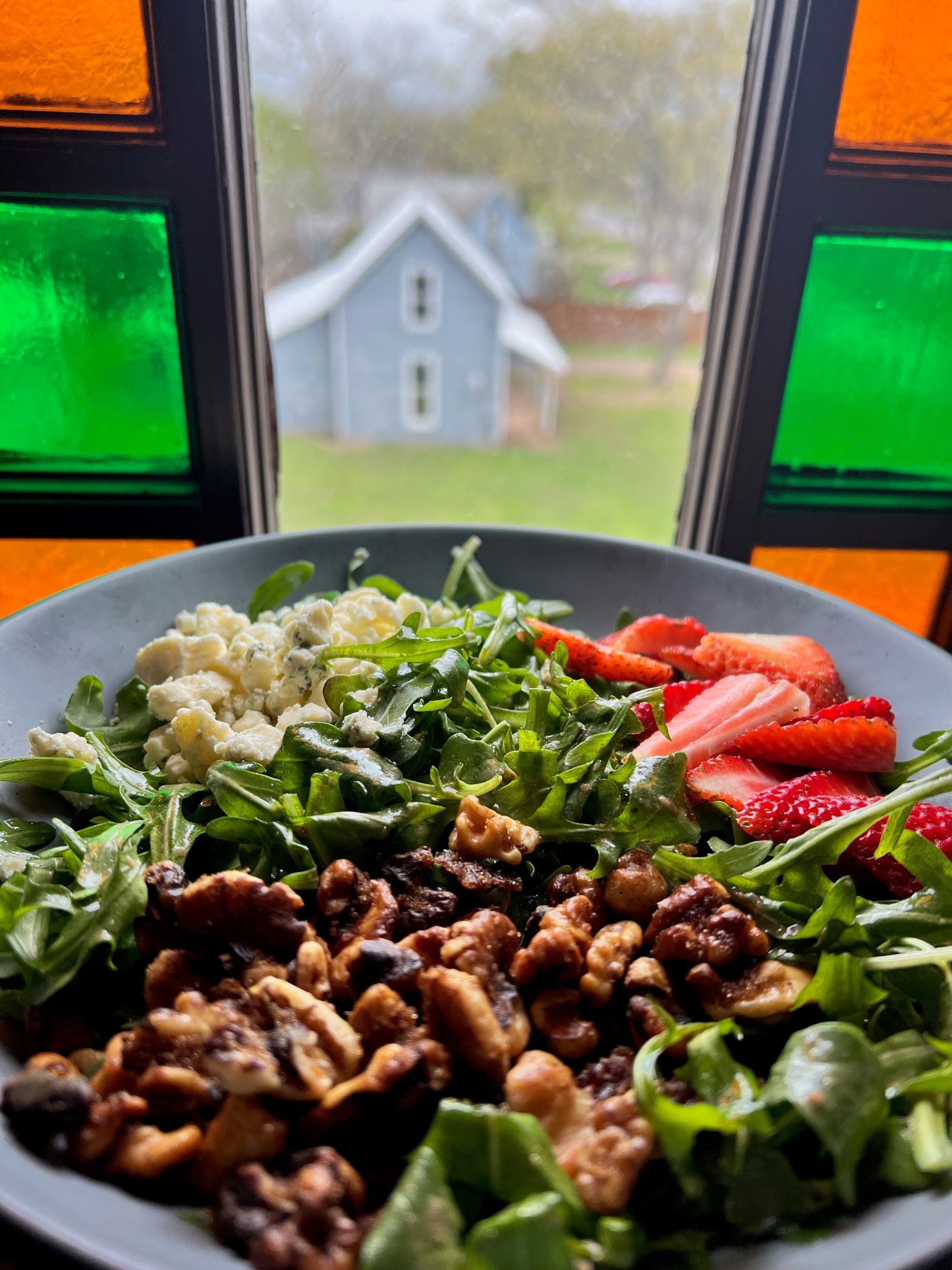 Colorful salad with rich greens, ripe strawberries, candied pecans, and goat cheese.